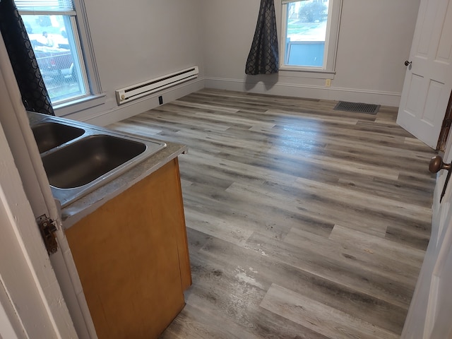 kitchen with sink, a baseboard heating unit, and light wood-type flooring