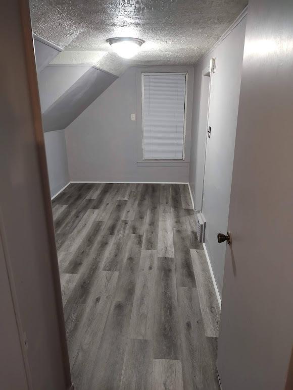706 W Front, Bloomington, IL 61701 - additional living space with a textured ceiling, wood finished floors, vaulted ceiling, and baseboards