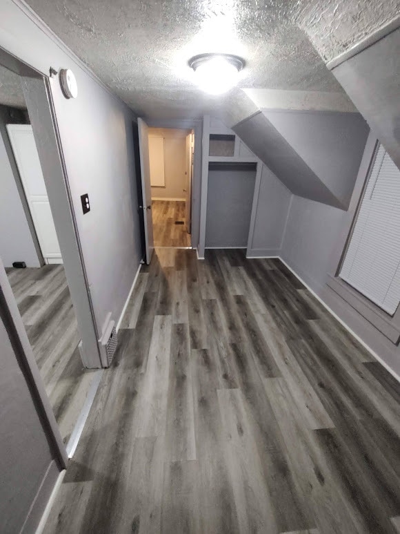 bonus room featuring a textured ceiling, vaulted ceiling, and dark hardwood / wood-style flooring