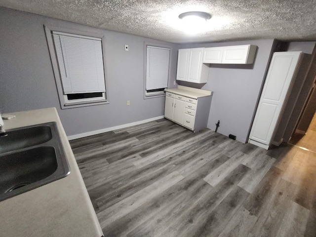 interior space with sink, dark wood-type flooring, white cabinets, and a textured ceiling