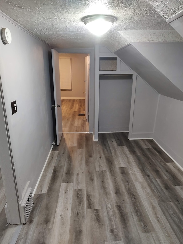 bonus room featuring lofted ceiling, a textured ceiling, and dark hardwood / wood-style flooring