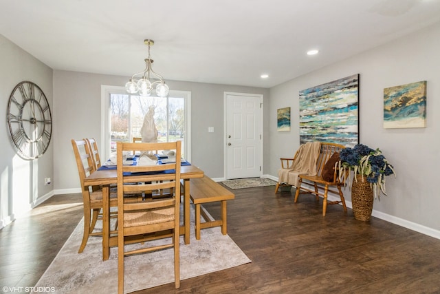 dining space with dark hardwood / wood-style floors and an inviting chandelier