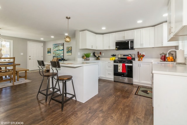 kitchen with white cabinets, dark hardwood / wood-style flooring, decorative light fixtures, and appliances with stainless steel finishes