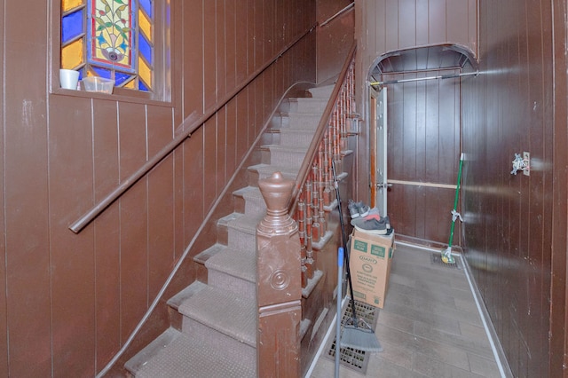 stairs with hardwood / wood-style floors and wooden walls