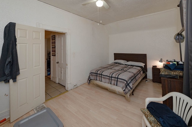 bedroom featuring light hardwood / wood-style flooring, a textured ceiling, and ceiling fan