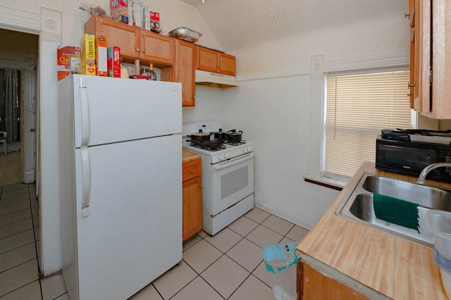 kitchen with sink, a textured ceiling, white appliances, and light tile patterned floors