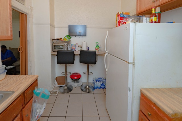 kitchen featuring light tile patterned flooring and white refrigerator