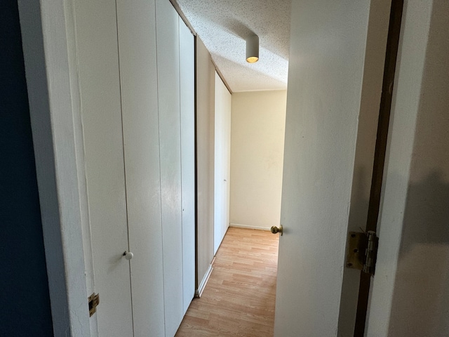 hallway featuring light hardwood / wood-style flooring and a textured ceiling