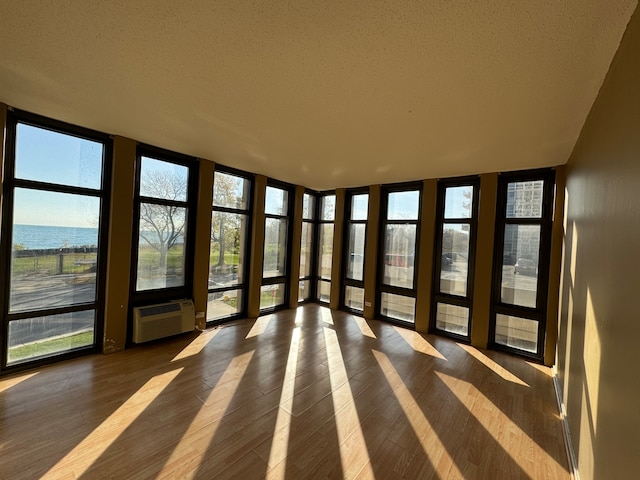 unfurnished sunroom with a wall mounted AC and a water view