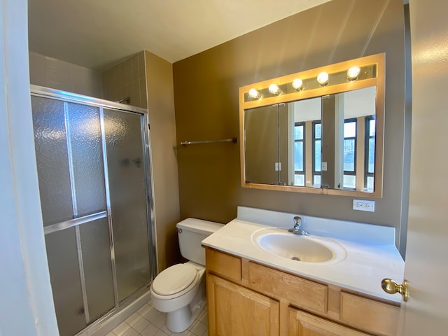 bathroom featuring toilet, vanity, tile patterned floors, and a shower with door