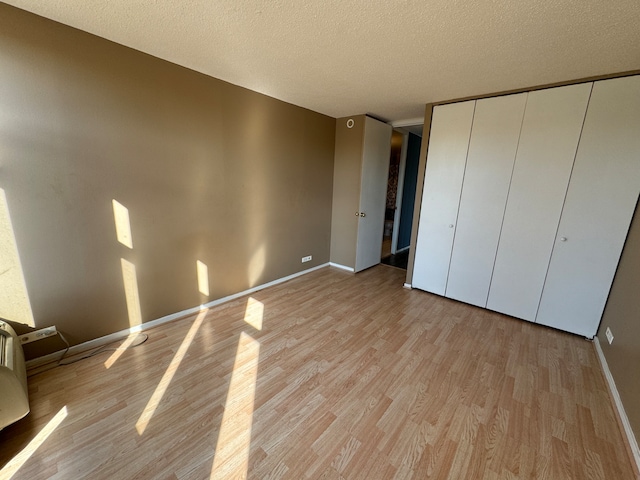 unfurnished bedroom with a closet, a textured ceiling, and light wood-type flooring