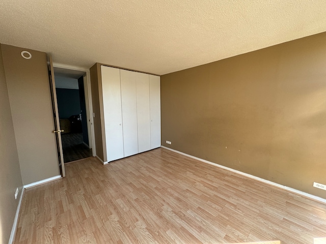 unfurnished bedroom featuring a closet, a textured ceiling, and light wood-type flooring