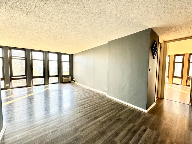 spare room with an AC wall unit, a textured ceiling, and dark hardwood / wood-style flooring