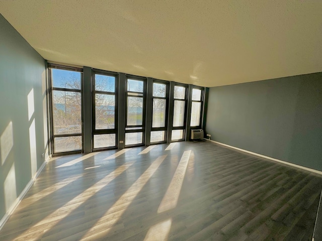 empty room featuring a wall mounted air conditioner, a textured ceiling, and dark wood-type flooring