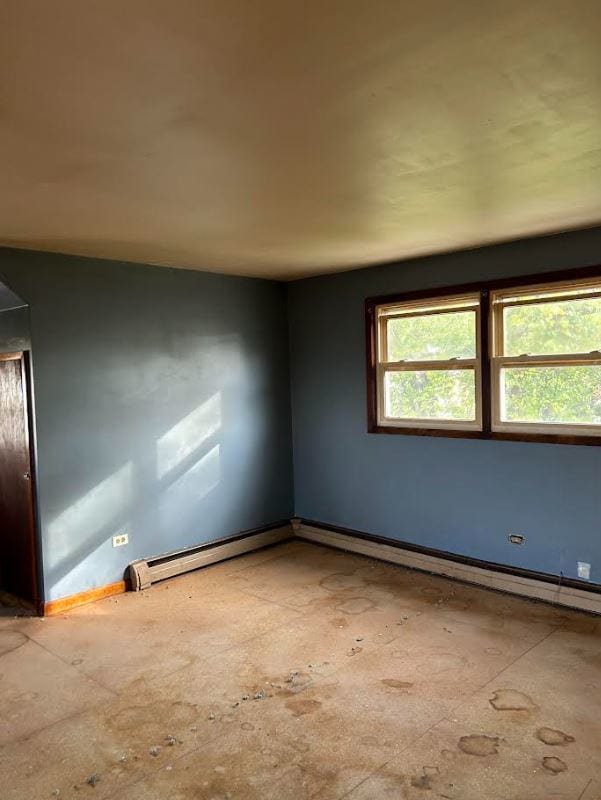 unfurnished room with a baseboard heating unit