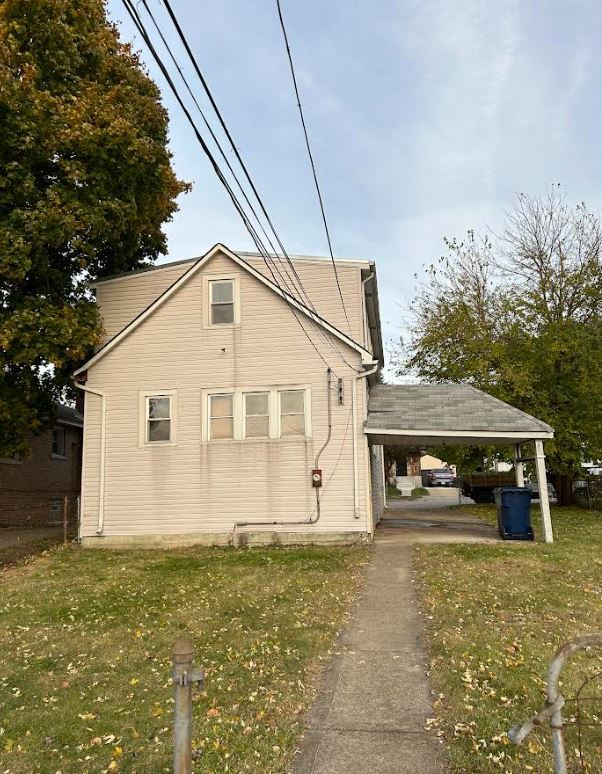 view of property exterior with a carport and a lawn