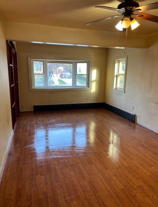 empty room featuring ceiling fan, plenty of natural light, and hardwood / wood-style floors