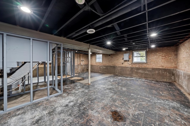 basement with electric panel and brick wall