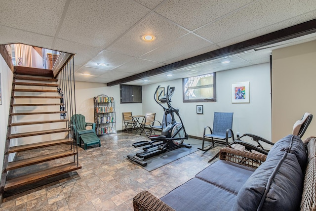 workout room with stone finish floor, recessed lighting, a paneled ceiling, and baseboards