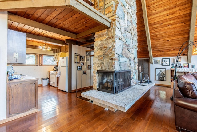 living area with beam ceiling, a stone fireplace, an inviting chandelier, wood ceiling, and dark wood-style flooring