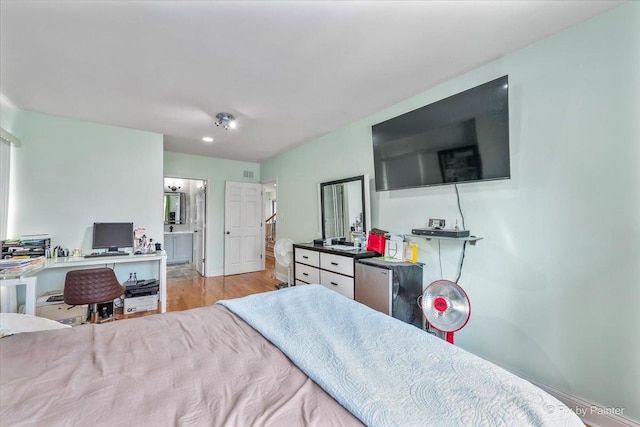 bedroom with wood finished floors and freestanding refrigerator