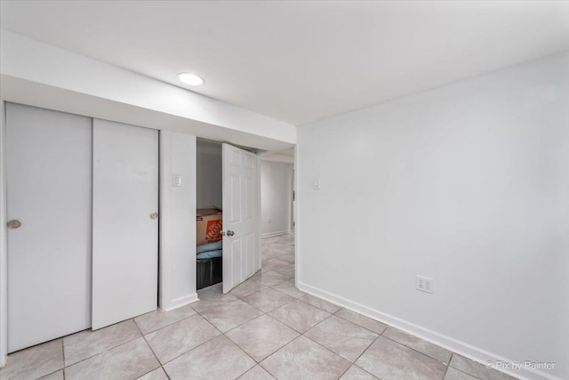 unfurnished bedroom featuring light tile patterned floors, baseboards, and a closet