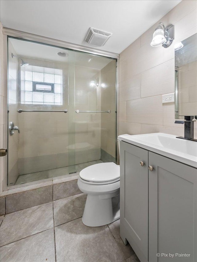 full bathroom with visible vents, a shower stall, toilet, vanity, and tile walls