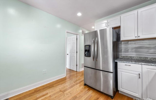 kitchen with baseboards, light wood-style flooring, stainless steel refrigerator with ice dispenser, white cabinets, and stone countertops