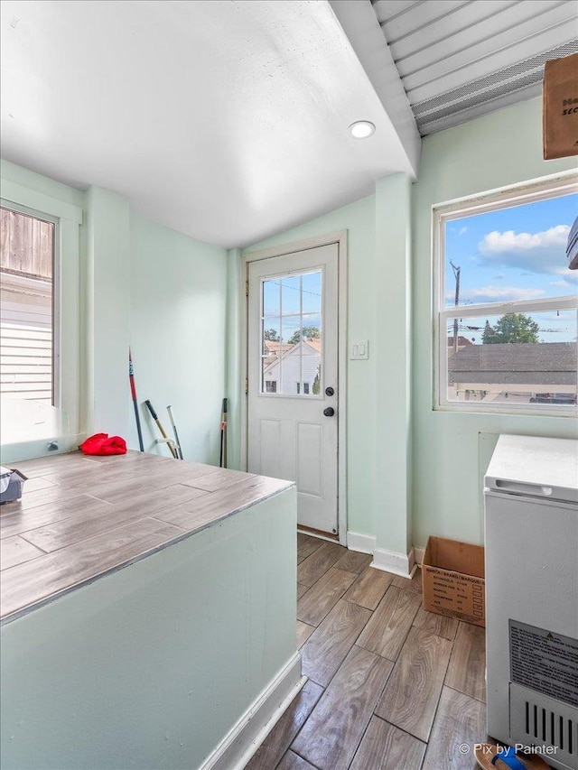 kitchen featuring baseboards, wood finished floors, and vaulted ceiling