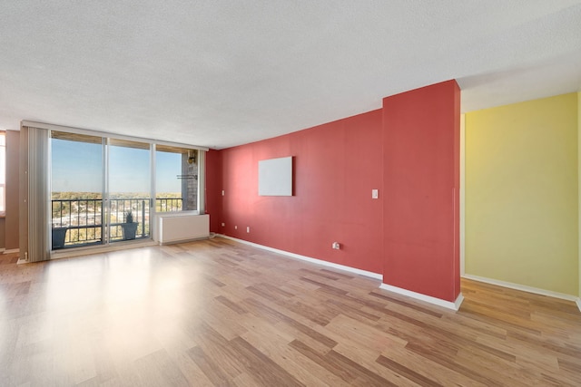 spare room featuring a wall of windows, a textured ceiling, and light wood-type flooring