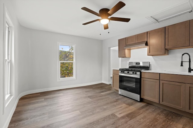 kitchen featuring hardwood / wood-style floors, sink, stainless steel gas stove, and ceiling fan