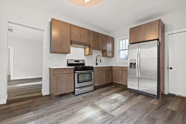 kitchen featuring appliances with stainless steel finishes, dark hardwood / wood-style floors, sink, and exhaust hood