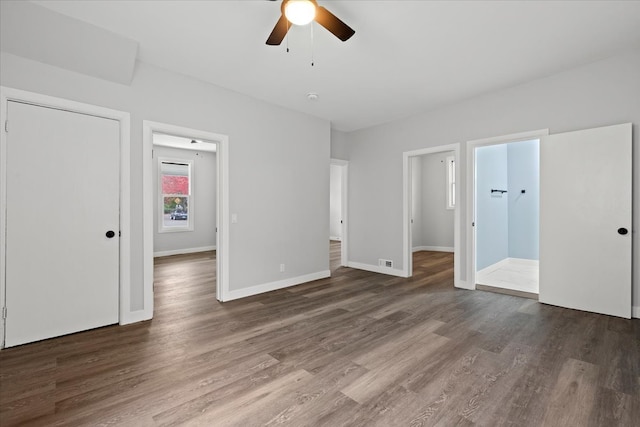 unfurnished bedroom featuring ensuite bathroom, dark wood-type flooring, and ceiling fan