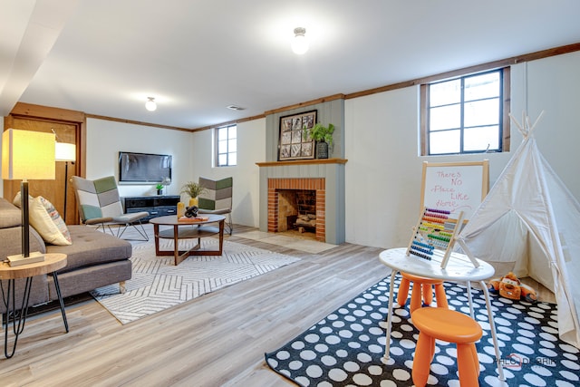 living room with light wood-type flooring, crown molding, a wealth of natural light, and a brick fireplace