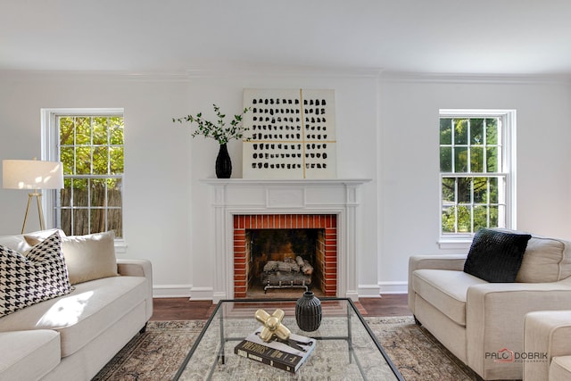 living room featuring dark hardwood / wood-style flooring, a brick fireplace, and a wealth of natural light