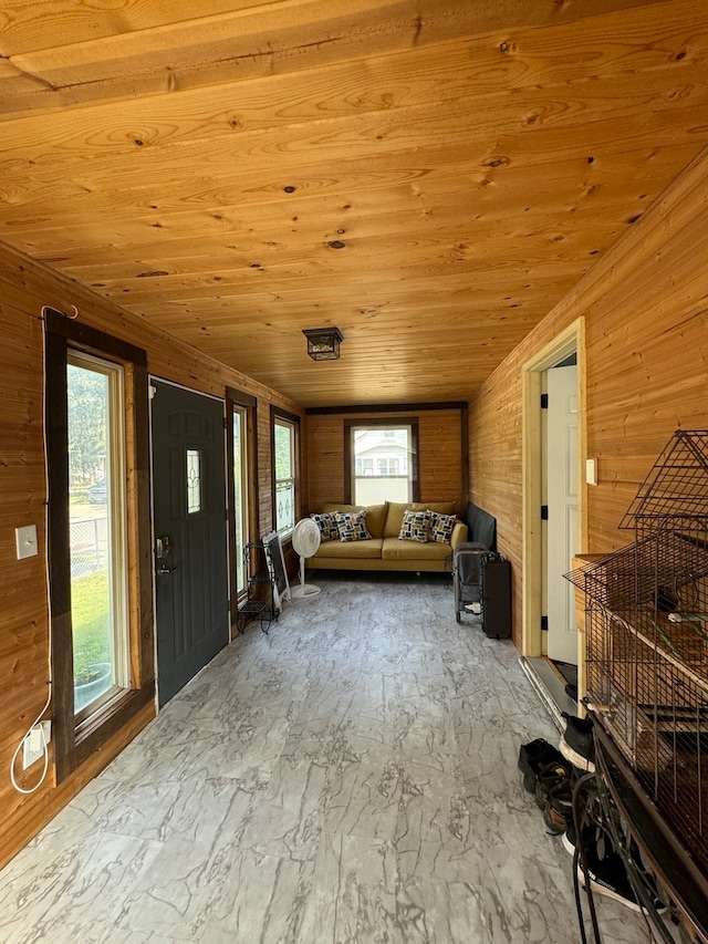 unfurnished living room featuring wood ceiling, a healthy amount of sunlight, lofted ceiling, and wooden walls