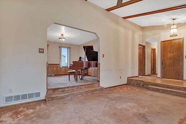 carpeted living room with beamed ceiling