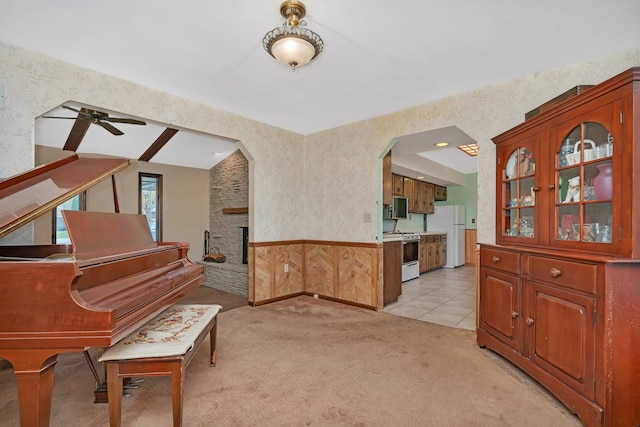 interior space with light carpet, a brick fireplace, and ceiling fan