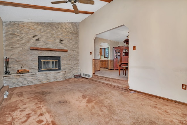 carpeted living room featuring a stone fireplace, ceiling fan, and lofted ceiling with beams