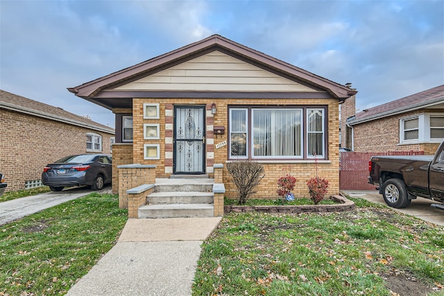 bungalow-style home featuring entry steps, brick siding, and a front yard