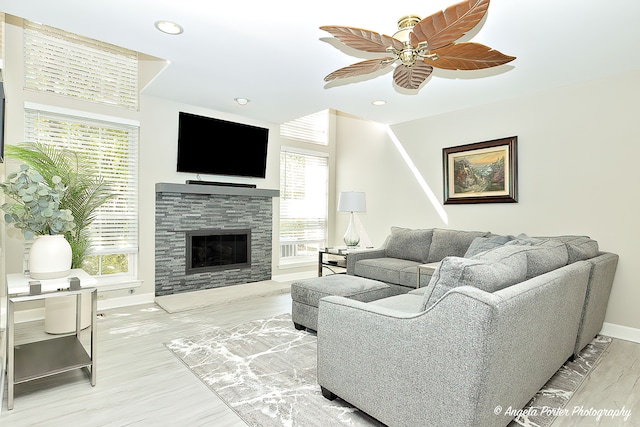 living room with a fireplace, a wealth of natural light, wood-type flooring, and ceiling fan