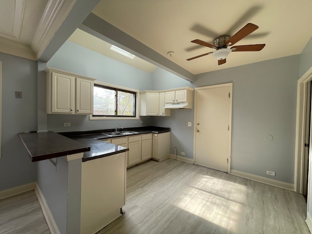 kitchen featuring kitchen peninsula, ceiling fan, sink, and light hardwood / wood-style flooring