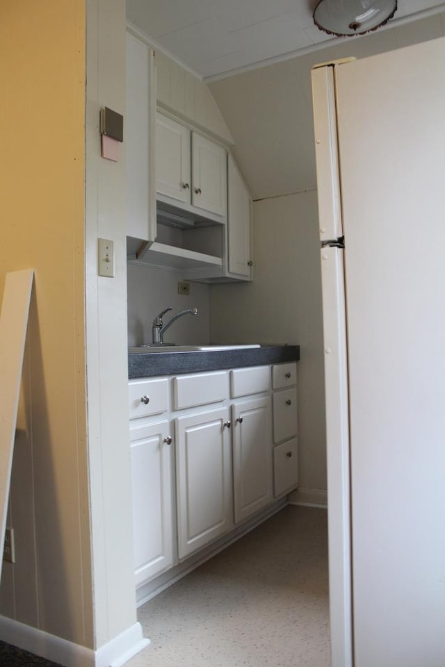 kitchen featuring white cabinetry, sink, vaulted ceiling, and white refrigerator