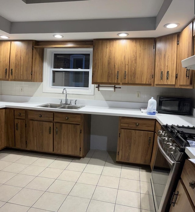 kitchen featuring light tile patterned floors, stainless steel stove, sink, and decorative backsplash