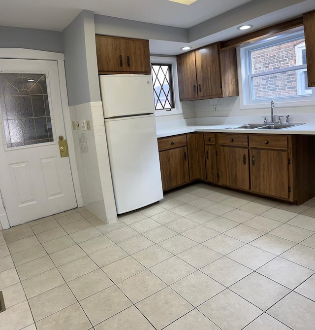 kitchen with light tile patterned flooring, sink, tasteful backsplash, dark brown cabinets, and white fridge