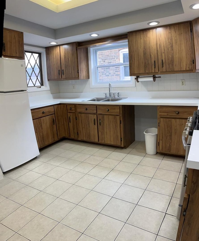 kitchen with plenty of natural light, a tray ceiling, sink, and white fridge