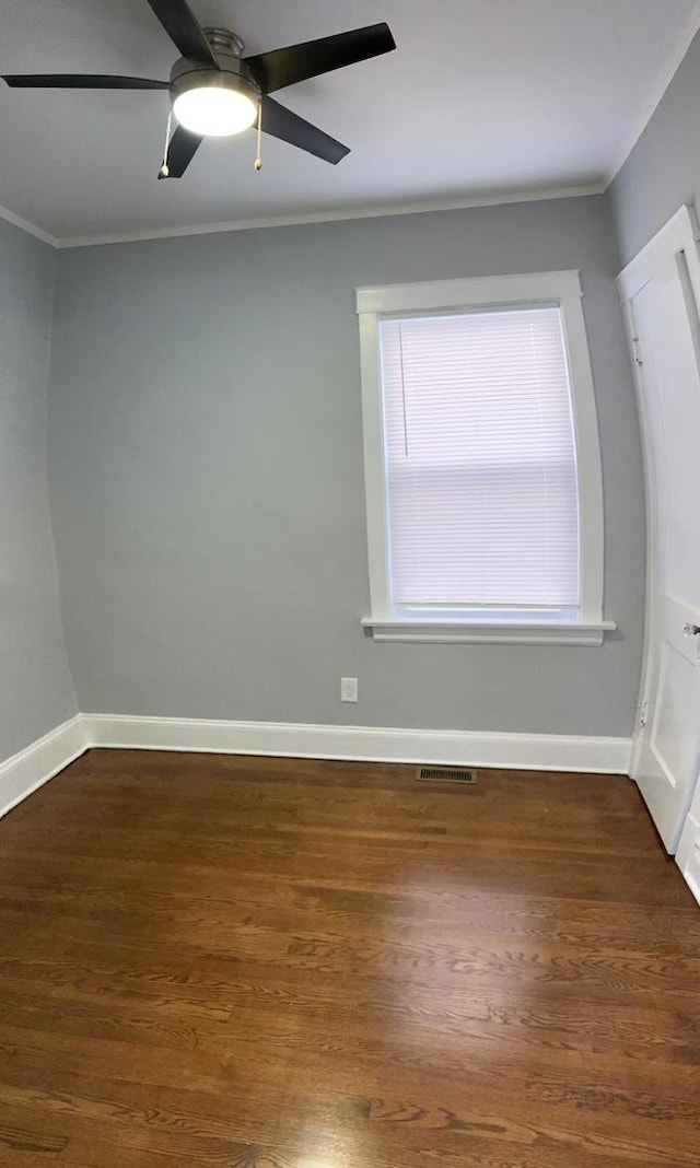 empty room featuring dark wood-type flooring, ceiling fan, and crown molding