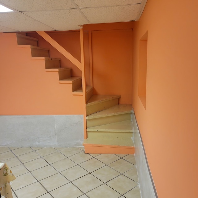 stairway with a paneled ceiling and tile patterned floors