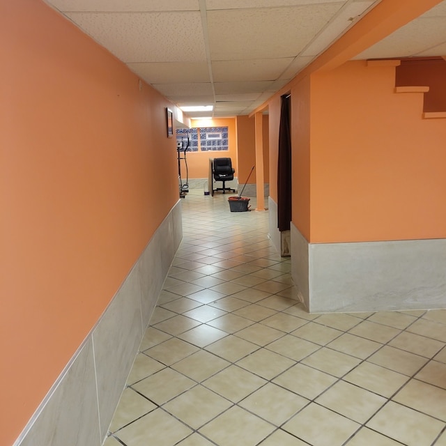 corridor featuring a paneled ceiling and light tile patterned floors