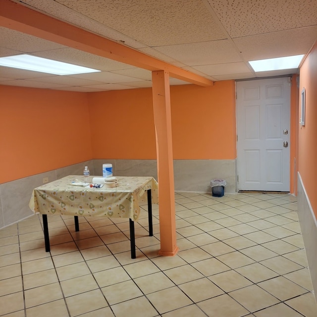 basement featuring a paneled ceiling and light tile patterned floors